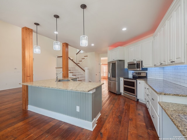 kitchen with dark hardwood / wood-style flooring, white cabinetry, appliances with stainless steel finishes, and hanging light fixtures