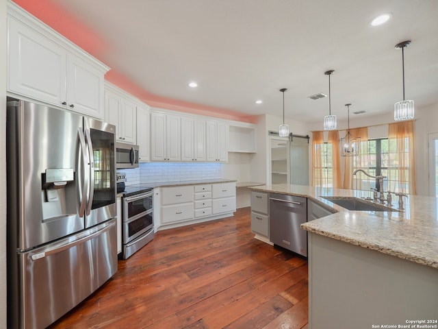 kitchen featuring white cabinetry, appliances with stainless steel finishes, light stone countertops, a barn door, and dark hardwood / wood-style flooring