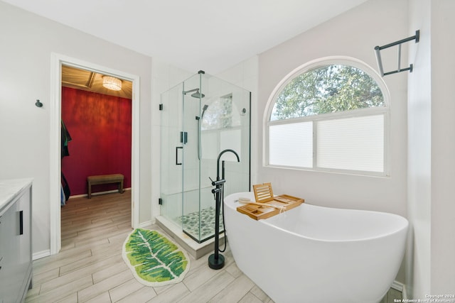 bathroom featuring hardwood / wood-style floors, vanity, and plus walk in shower