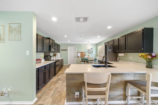 kitchen with a kitchen breakfast bar, black range with electric cooktop, sink, and light wood-type flooring