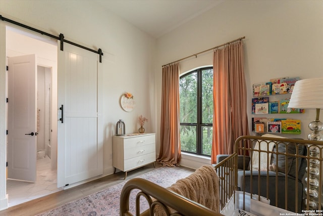 bedroom with a crib, light hardwood / wood-style flooring, and a barn door