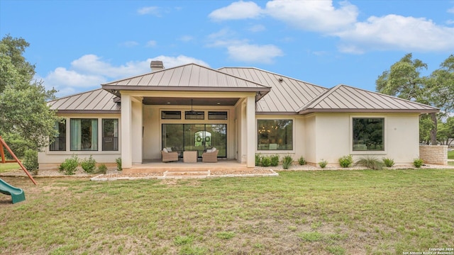 back of property featuring a playground and a lawn