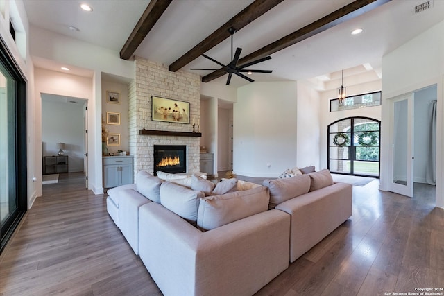 living room featuring hardwood / wood-style flooring, beamed ceiling, ceiling fan, a fireplace, and a high ceiling