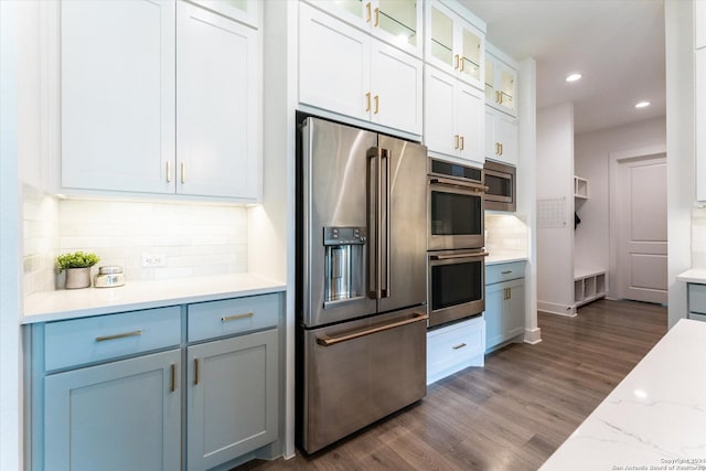 kitchen with stainless steel appliances, white cabinetry, light stone counters, tasteful backsplash, and dark hardwood / wood-style flooring