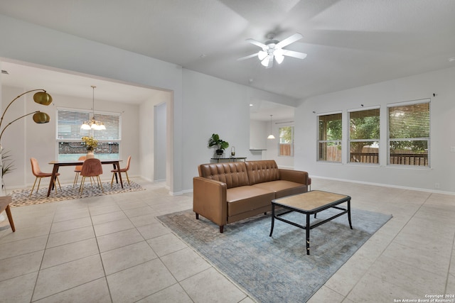 tiled living room featuring ceiling fan with notable chandelier