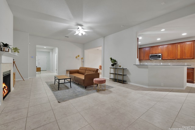 tiled living room featuring a fireplace and ceiling fan