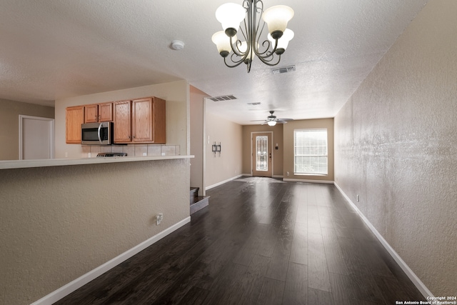 kitchen with ceiling fan with notable chandelier, dark wood-type flooring, a textured ceiling, and decorative light fixtures