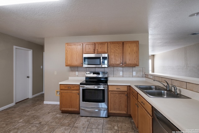 kitchen with a textured ceiling, sink, backsplash, and appliances with stainless steel finishes