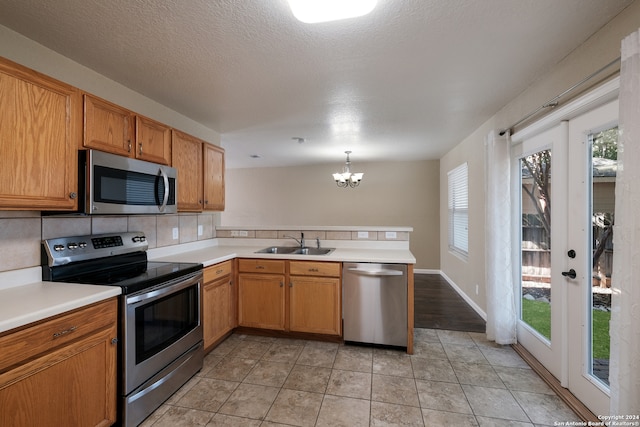 kitchen featuring stainless steel appliances, decorative backsplash, kitchen peninsula, sink, and pendant lighting