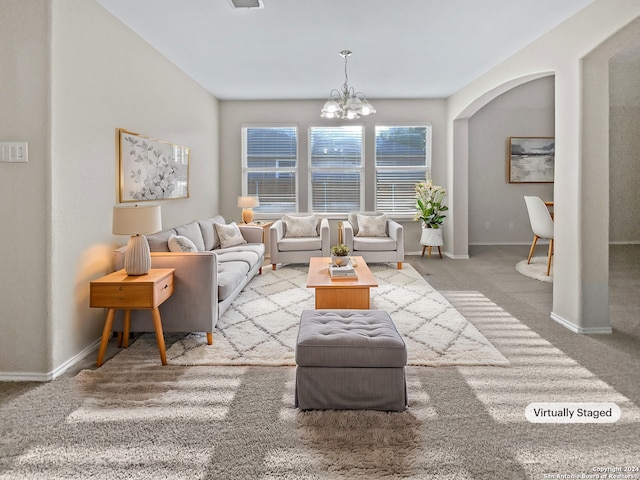 carpeted living room featuring an inviting chandelier