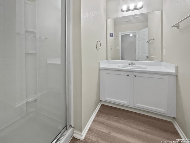 bathroom featuring vanity, wood-type flooring, and a shower with door