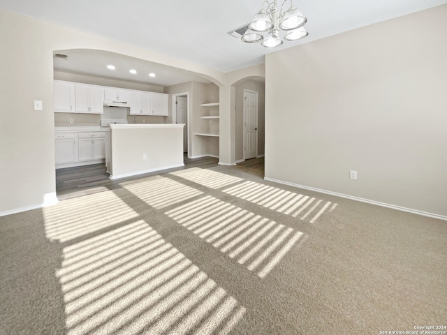 unfurnished living room with an inviting chandelier and dark carpet