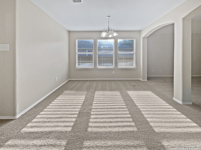 spare room featuring a chandelier and carpet floors