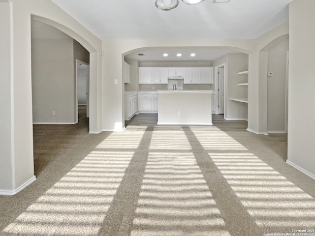 unfurnished living room featuring light colored carpet and built in features