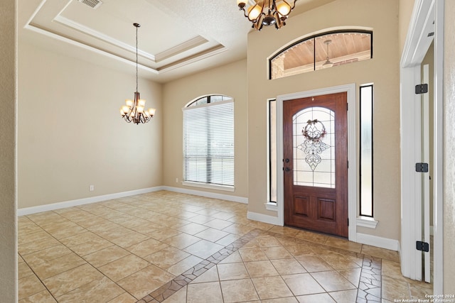 foyer featuring ornamental molding, light tile patterned floors, a raised ceiling, and a notable chandelier