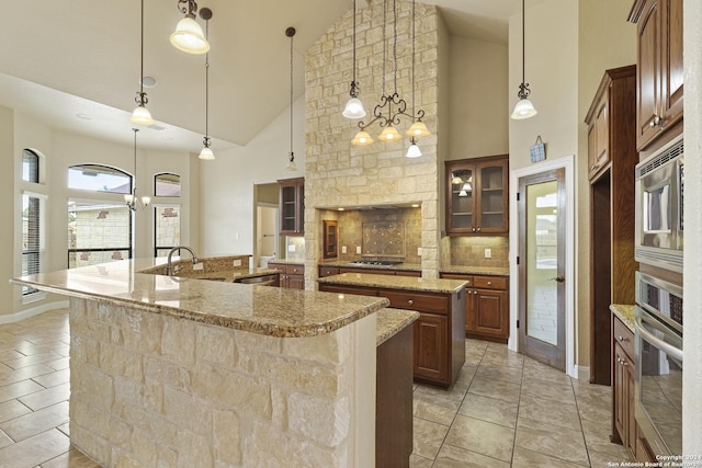 100 Vintage Ranch Cir, La Vernia, TX 78121 - kitchen with a large island, appliances with stainless steel finishes, high vaulted ceiling, glass insert cabinets, and a sink