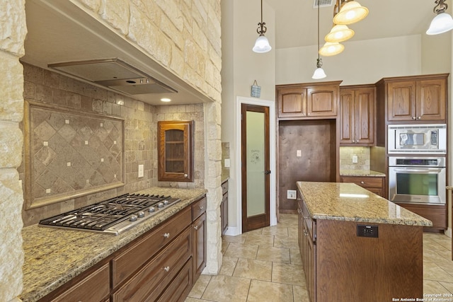 100 Vintage Ranch Cir, La Vernia, TX 78121 - kitchen with stainless steel appliances, light stone counters, tasteful backsplash, a center island, and decorative light fixtures
