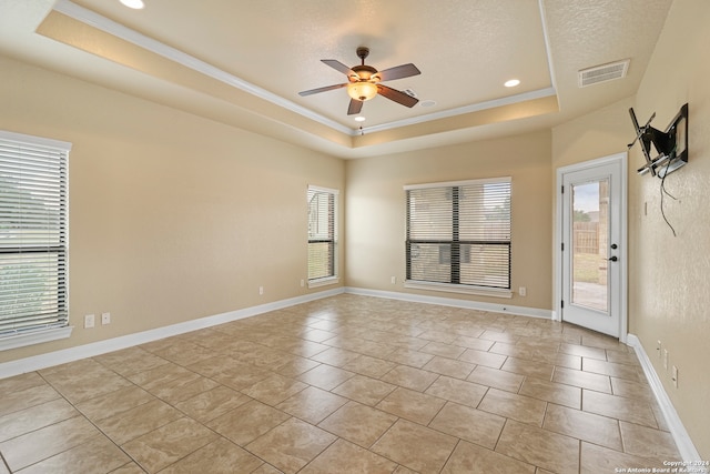 spare room with a textured ceiling, ceiling fan, a raised ceiling, and crown molding