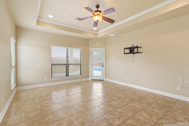 tiled empty room featuring ceiling fan, a raised ceiling, and crown molding