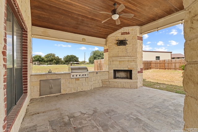 view of patio with an outdoor kitchen, an outdoor stone fireplace, ceiling fan, sink, and a grill