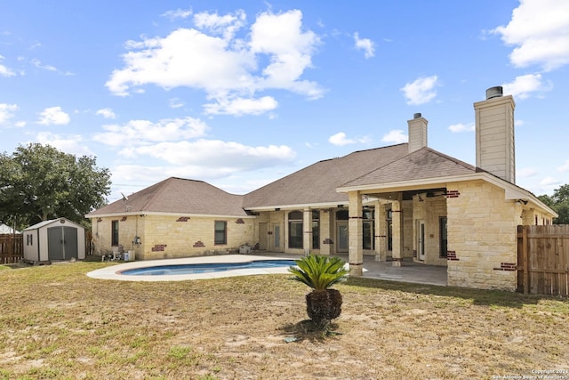 back of house with a fenced in pool, a storage unit, and a patio area