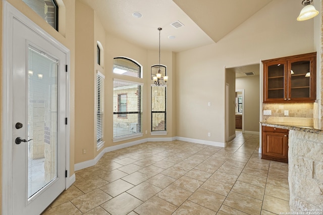 unfurnished dining area featuring a chandelier, high vaulted ceiling, and light tile patterned flooring