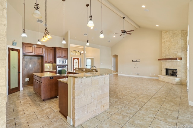 kitchen with ceiling fan, stainless steel appliances, hanging light fixtures, high vaulted ceiling, and a spacious island