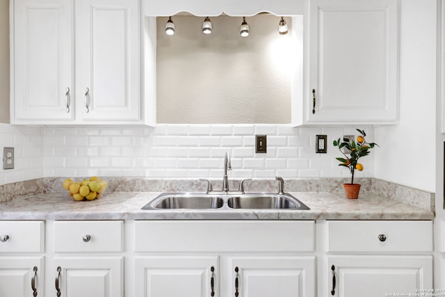 kitchen featuring white cabinets, light stone countertops, sink, and backsplash