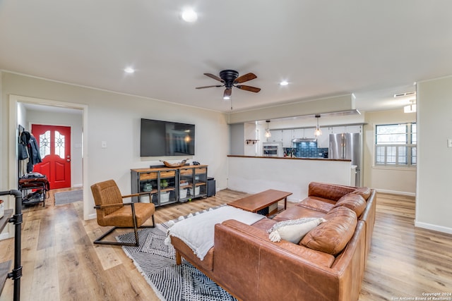 living room featuring light hardwood / wood-style floors, ceiling fan, and ornamental molding