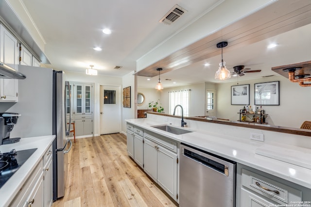 kitchen with light wood-type flooring, appliances with stainless steel finishes, decorative light fixtures, sink, and white cabinets