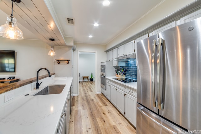 kitchen featuring stainless steel appliances, light stone counters, sink, light wood-type flooring, and decorative light fixtures