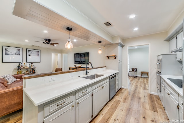 kitchen featuring stainless steel appliances, decorative light fixtures, sink, ceiling fan, and light hardwood / wood-style flooring