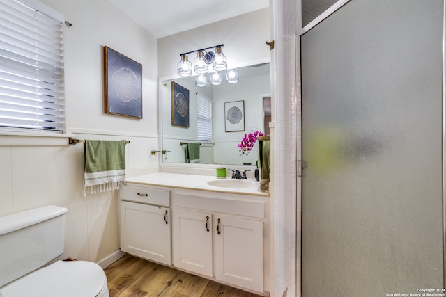 bathroom with hardwood / wood-style floors, vanity, toilet, and a shower with shower door