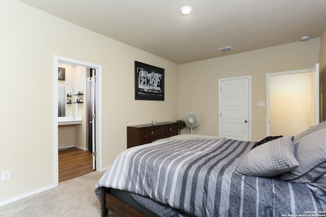 bedroom featuring a textured ceiling, light carpet, and ensuite bathroom