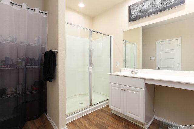 bathroom featuring hardwood / wood-style flooring, a shower with door, and vanity