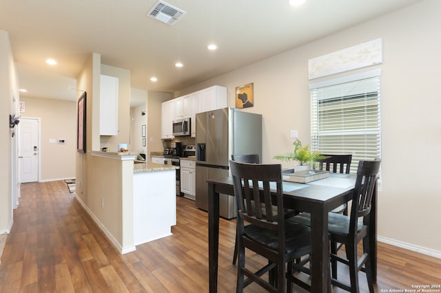 kitchen with white cabinetry, light stone counters, dark hardwood / wood-style floors, and stainless steel appliances