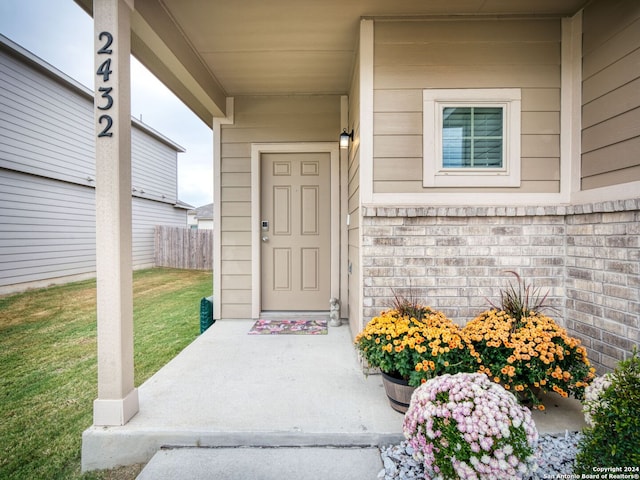 view of exterior entry featuring a lawn