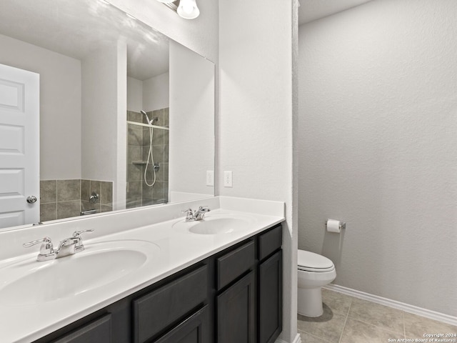 bathroom featuring vanity, tile patterned flooring, toilet, and tiled shower