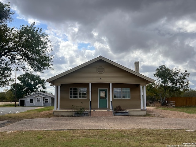 bungalow featuring covered porch and a front lawn