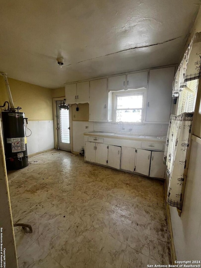 kitchen featuring white cabinetry, sink, and gas water heater