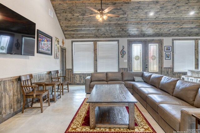 living room featuring french doors, ceiling fan, lofted ceiling, and wooden walls