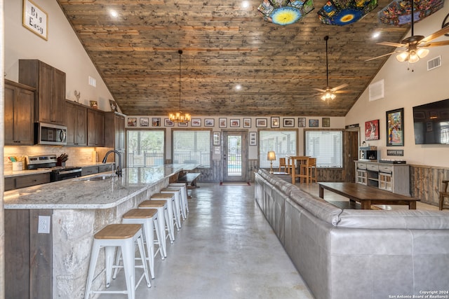 kitchen with an island with sink, appliances with stainless steel finishes, high vaulted ceiling, and sink