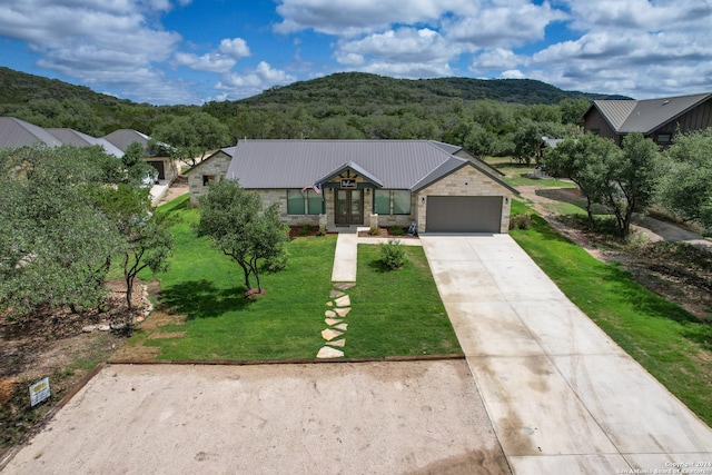 view of front facade with french doors, a garage, a mountain view, and a front yard