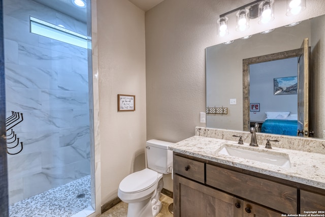 bathroom with a tile shower, vanity, and toilet