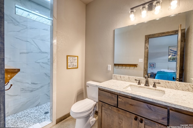 bathroom featuring vanity, tiled shower, and toilet