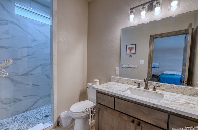 bathroom featuring a tile shower, vanity, and toilet