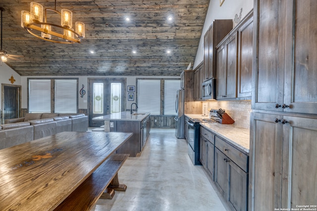 kitchen featuring sink, stainless steel appliances, light stone countertops, an island with sink, and decorative light fixtures