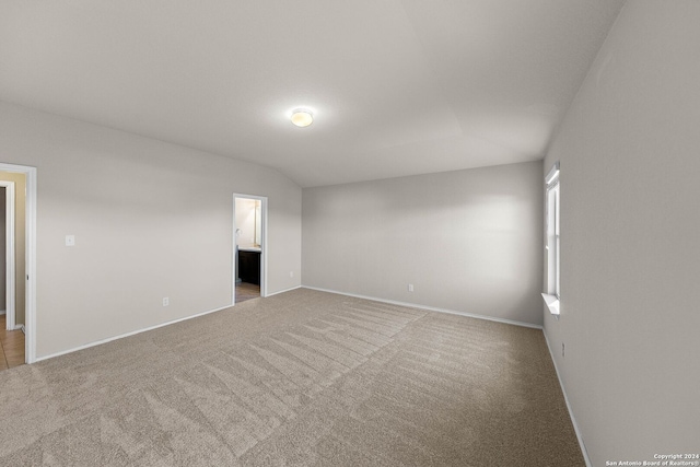 carpeted empty room featuring lofted ceiling