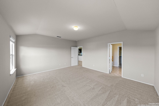 empty room featuring vaulted ceiling and light colored carpet