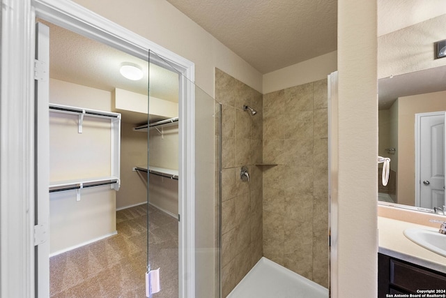 bathroom with vanity, a textured ceiling, and a tile shower